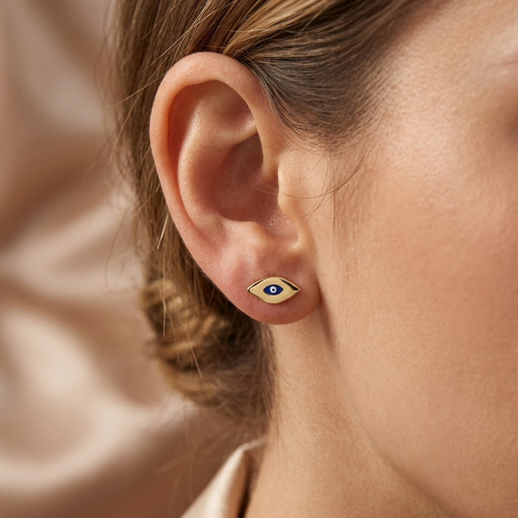 Close-up of an female model wearing a gold evil eye earring stud