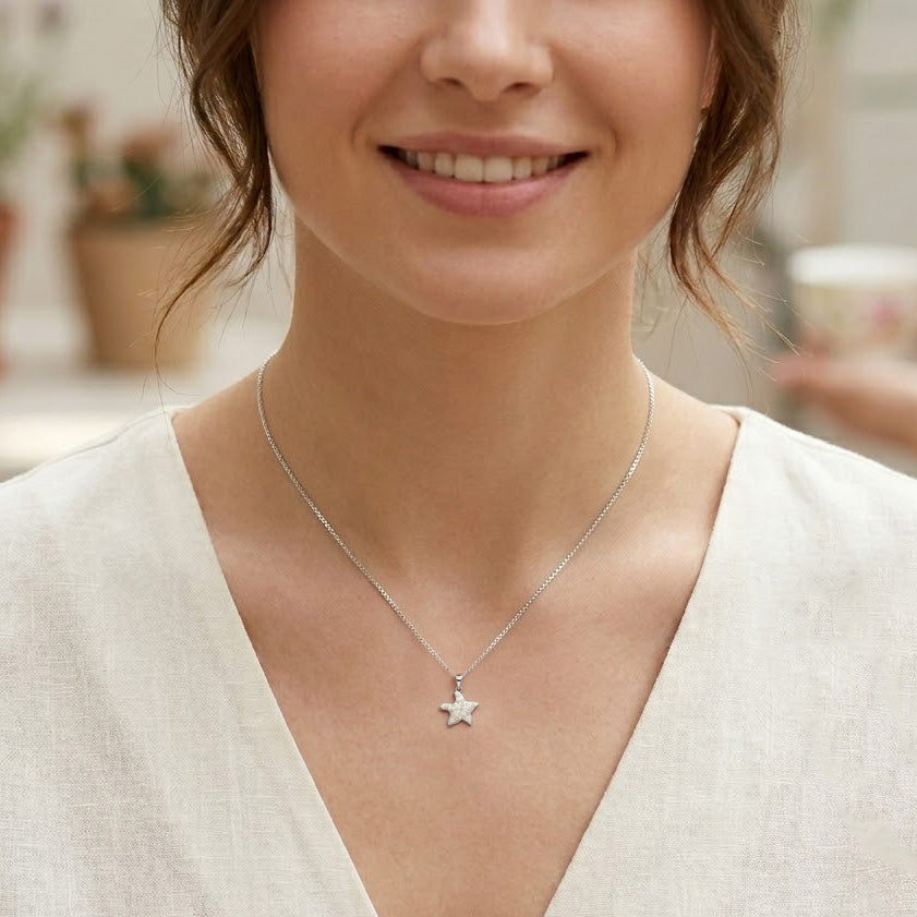 Woman wearing a silver starfish necklace with a blurred background