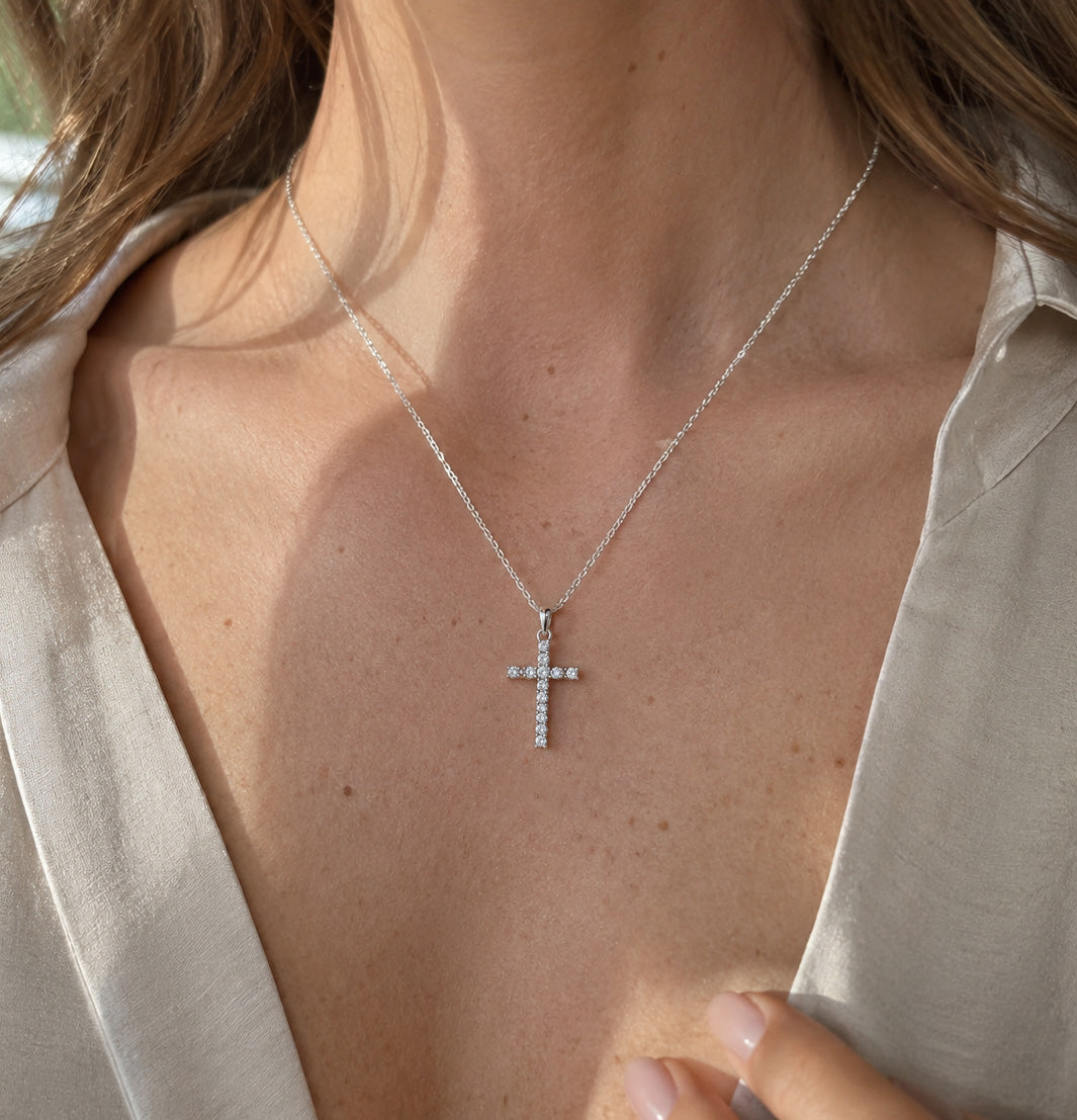 Silver cross necklace on a person wearing a light-colored shirt