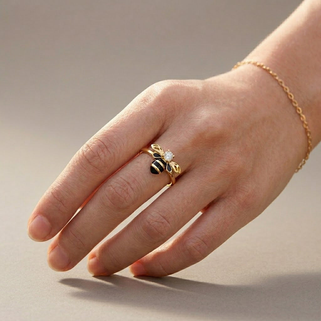 Hand wearing a gold ring with a black and yellow design on a neutral background