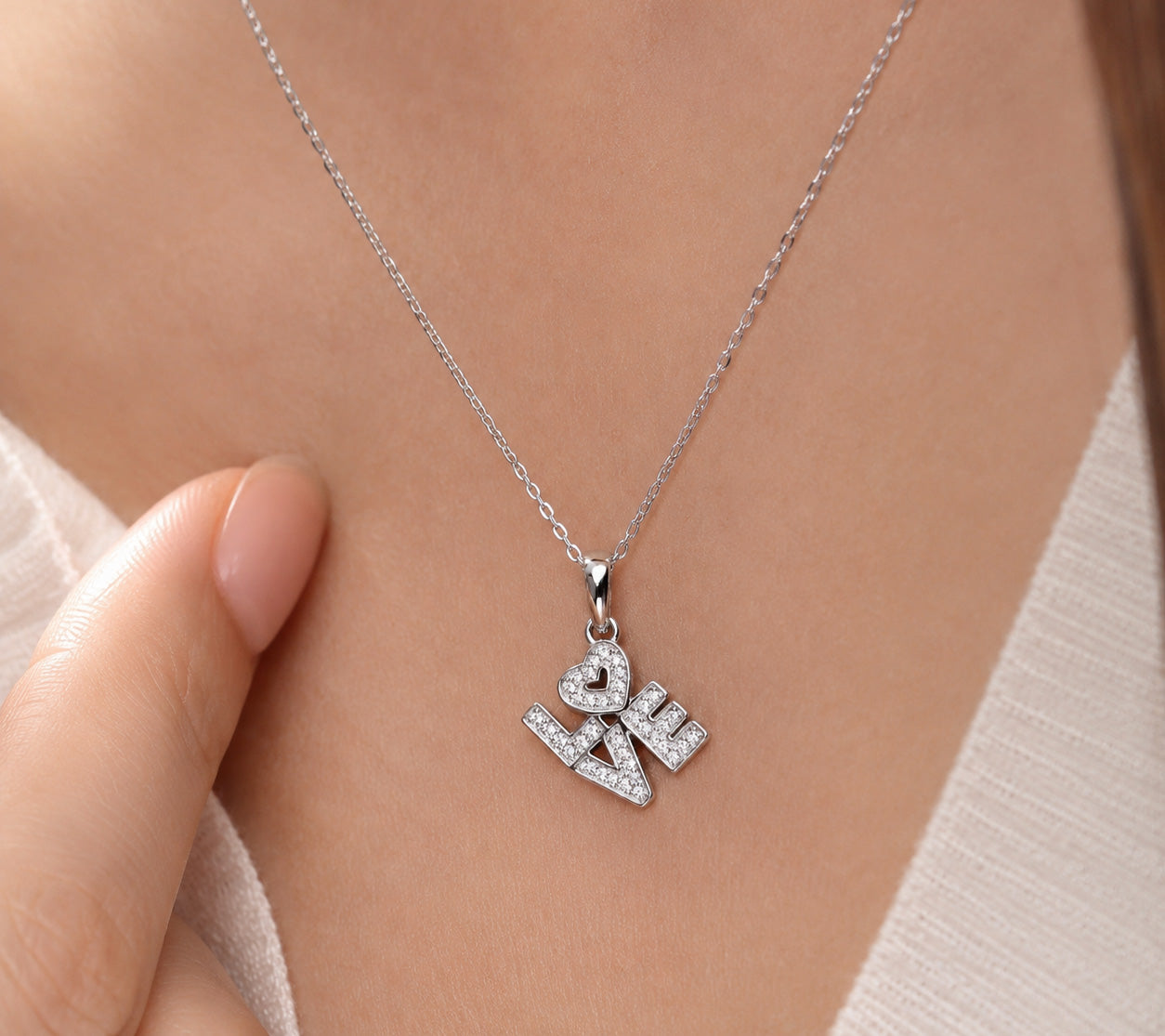 Silver necklace with 'LOVE' pendant on a person's neck