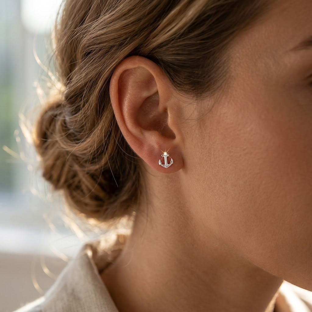 Close-up of an ear wearing a small anchor earring with blurred background