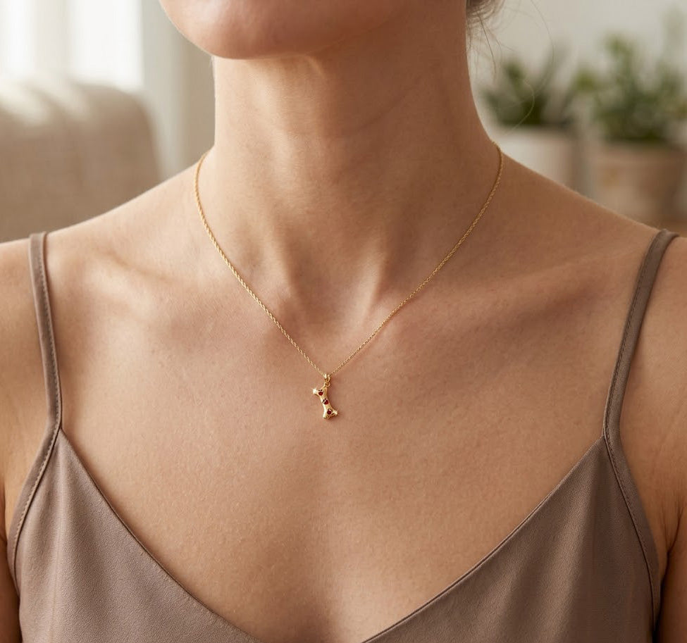 Necklace with a dog bone pendant worn by a person, with a neutral background