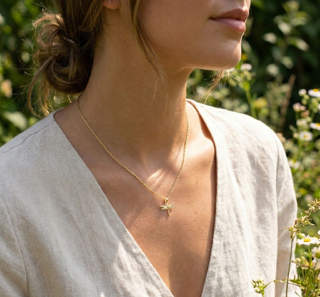Woman wearing a gold necklace with a delicate pendant outdoors