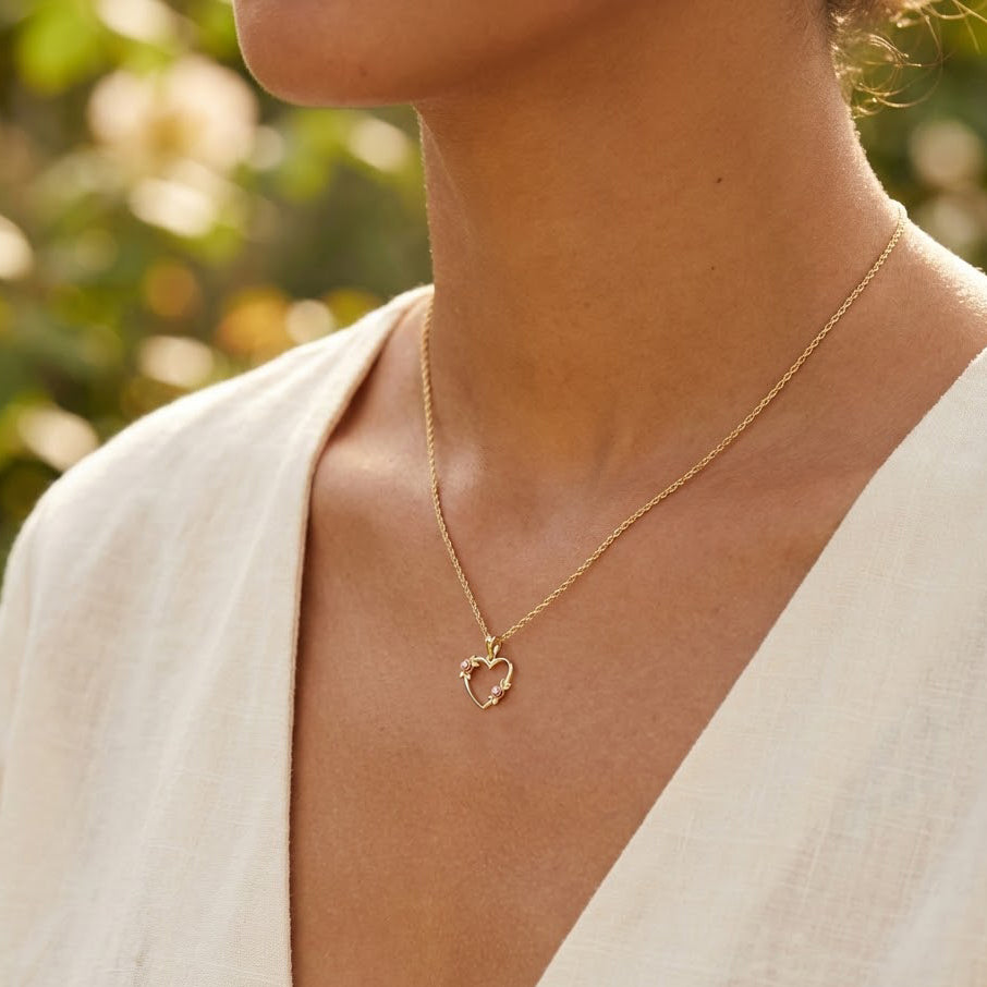 gold heart pendant with floral design worn by female mdoel