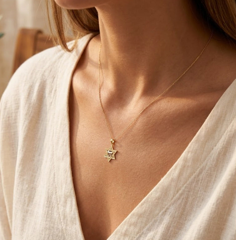 Close-up of a person wearing a gold necklace with a star of david pendant.