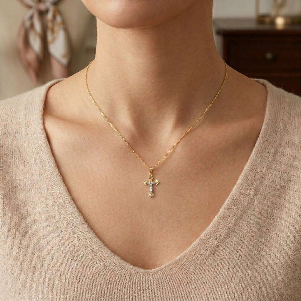 Gold necklace with a Jesus crucifix cross pendant worn by a person in a beige sweater.