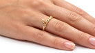 Gold love ring on a person's finger against a white background