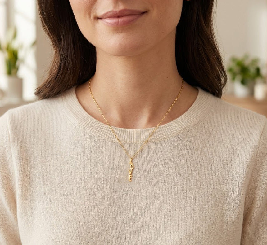 Woman wearing a gold necklace with a key pendant indoors.