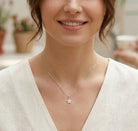 Woman wearing a silver starfish necklace with a blurred background