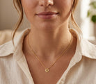 Close-up of a person wearing a gold necklace with a small pendant.