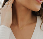 Close-up of a person wearing a delicate gold necklace with a small pendant.