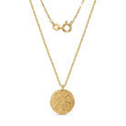 A gold necklace featuring a textured, soccer-ball-inspired circular pendant on a delicate gold chain, shown against a plain white background.