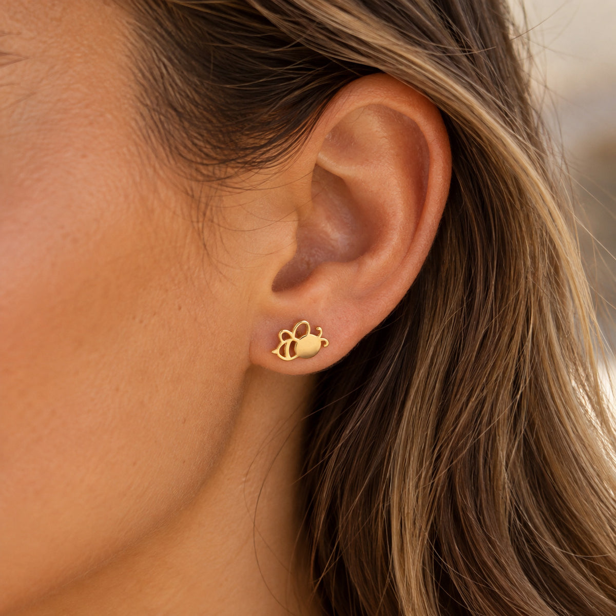gold bee earring worn by model 
