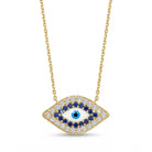 Gold-tone evil eye pendant necklace with a blue center eye, surrounded by a halo of white and dark blue stones, suspended on a delicate gold chain against a white background.