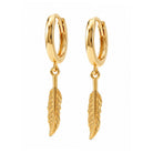 A pair of gold huggie hoop earrings with dangling feather charms, shown on a plain white background.