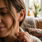 [group: silver-aries] Close-up of a woman wearing a aries shaped earring indoors.