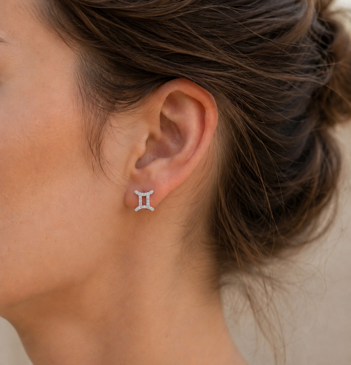 [group:silver-gemini]  Close-up of an ear wearing a silver earring with a blurred background