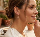 model wearing gold cross earring 