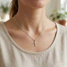 silver cross necklace worn by female model 
