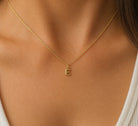 [group: e-10k-gold] A delicate gold chain necklace with a small capital letter 'E' pendant, shown worn on a model's neck.