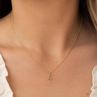[group: h-10k-gold]A delicate gold chain necklace with a small initial 'H' pendant, worn on the neck of a model.
