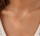 [group: p-10k-gold] A delicate gold chain necklace with a small letter 'P' initial pendant, worn on a model's neck over a white knit top.
