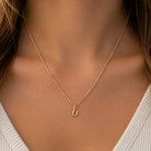 [group: u-10k-gold]A close-up of a model's neck and chest wearing a delicate gold chain necklace with a small U-shaped initial pendant.