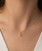 [group: w-10k-gold]A delicate gold chain necklace with a small, minimalist pendant worn by a model. The necklace is shown close-up against the model's neck and upper chest, wearing a white ribbed top.