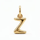 [group: z-10k-gold] A polished gold initial pendant charm shaped like the letter 'Z', featuring a smooth, reflective metallic finish and a top loop for attachment, shown on a clean white background.