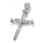 A silver cross pendant encrusted with clear gemstones, featuring a detailed hilt design and a polished pointed tip, shown on a clean white background.