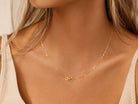 Close-up of a gold chain made with 14 karat gold  on a person wearing a beige top.