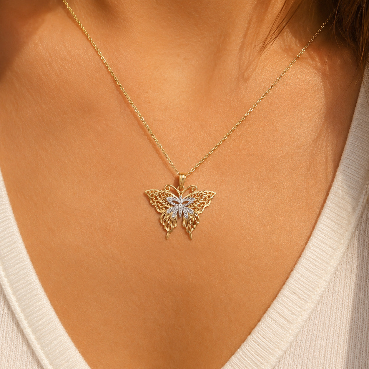 Gold butterfly pendant worn by female model on gold chain 