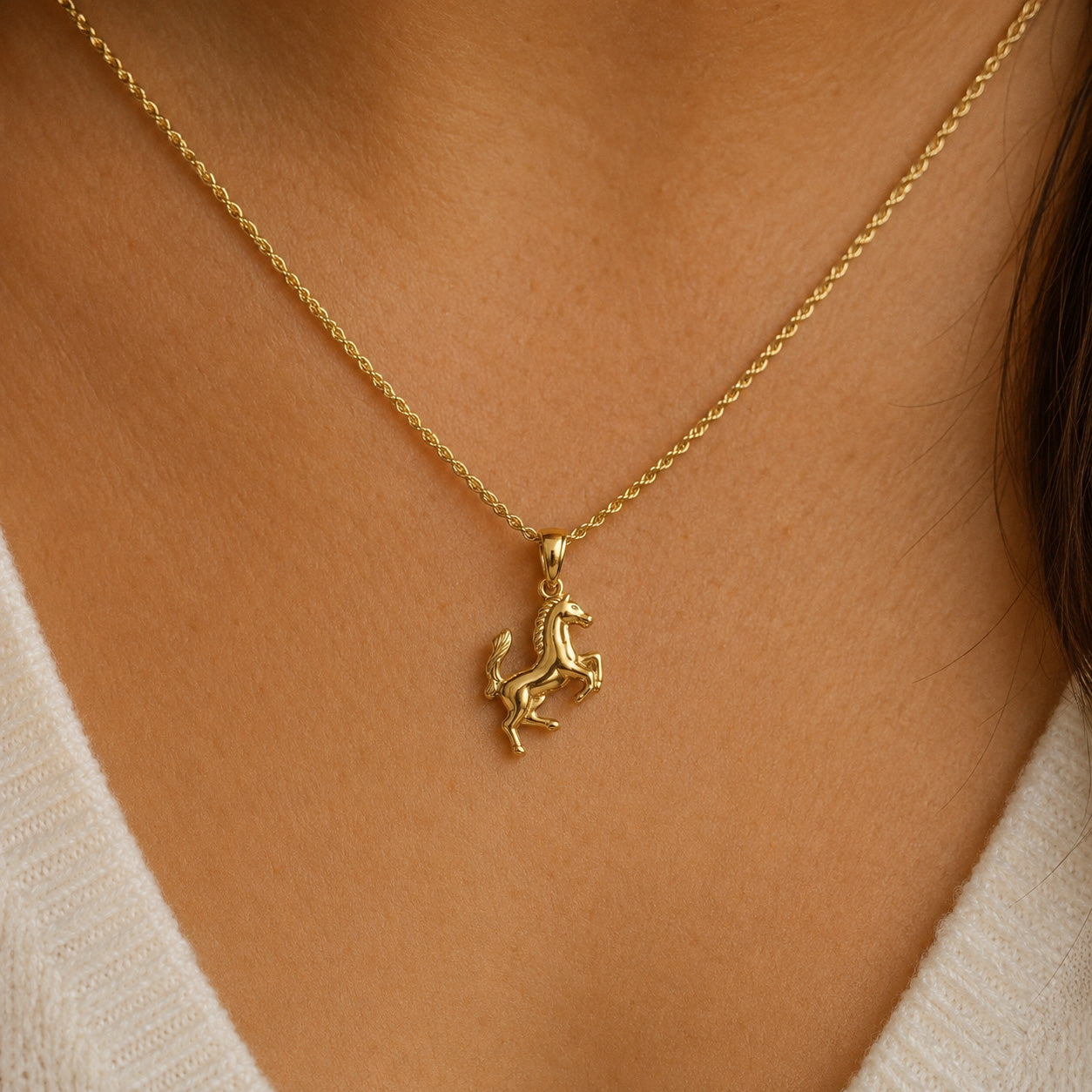 Gold necklace with a unicorn pendant on a person's neck