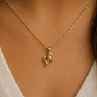 Gold necklace with a unicorn pendant on a person's neck