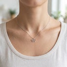 [group: silver] Butterfly necklace on a person wearing a white shirt with a blurred background