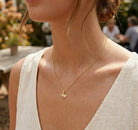 [group:gold-plated]Close-up of a person wearing a gold necklace with a heart pendant outdoors.