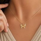 Gold butterfly necklace on a person's neck with a blurred background