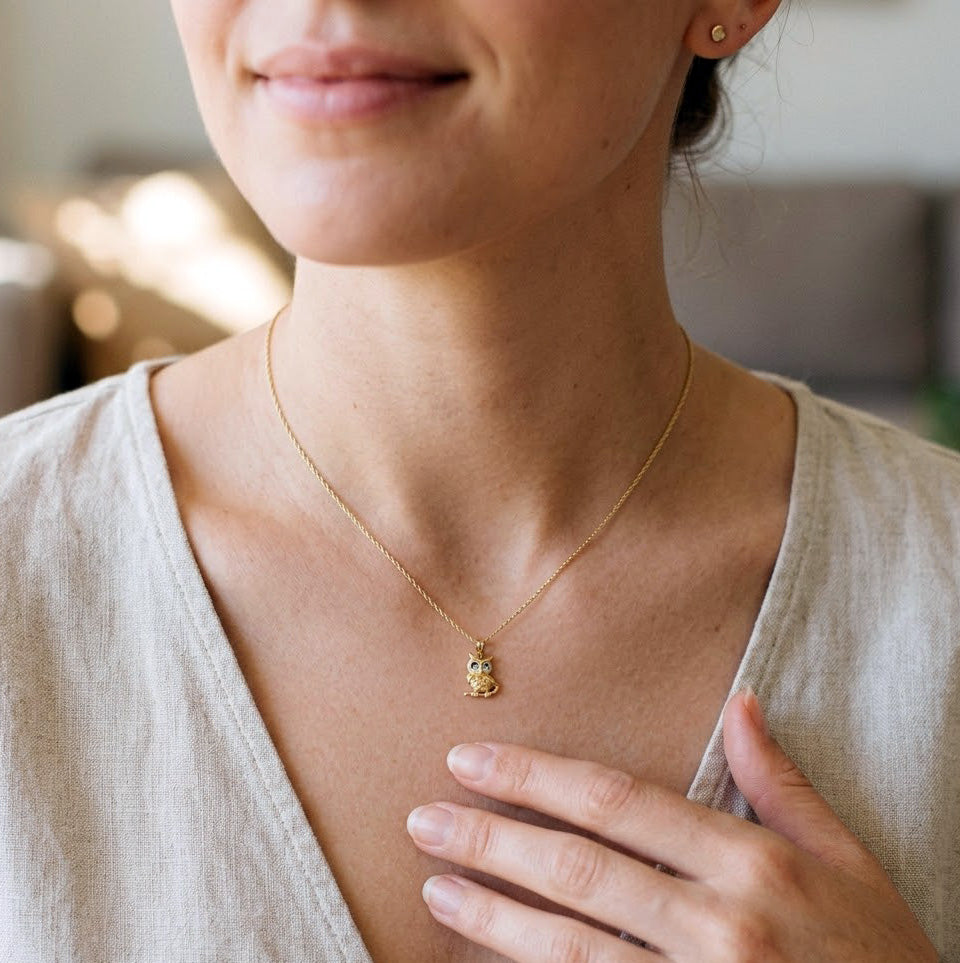 Woman wearing a gold necklace with a owl  pendant, blurred background