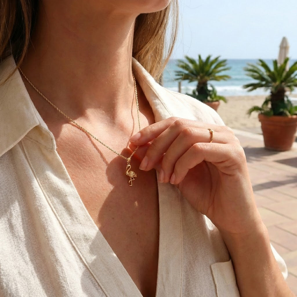 Woman wearing a flamingo gold necklace with a beach and palm trees in the background