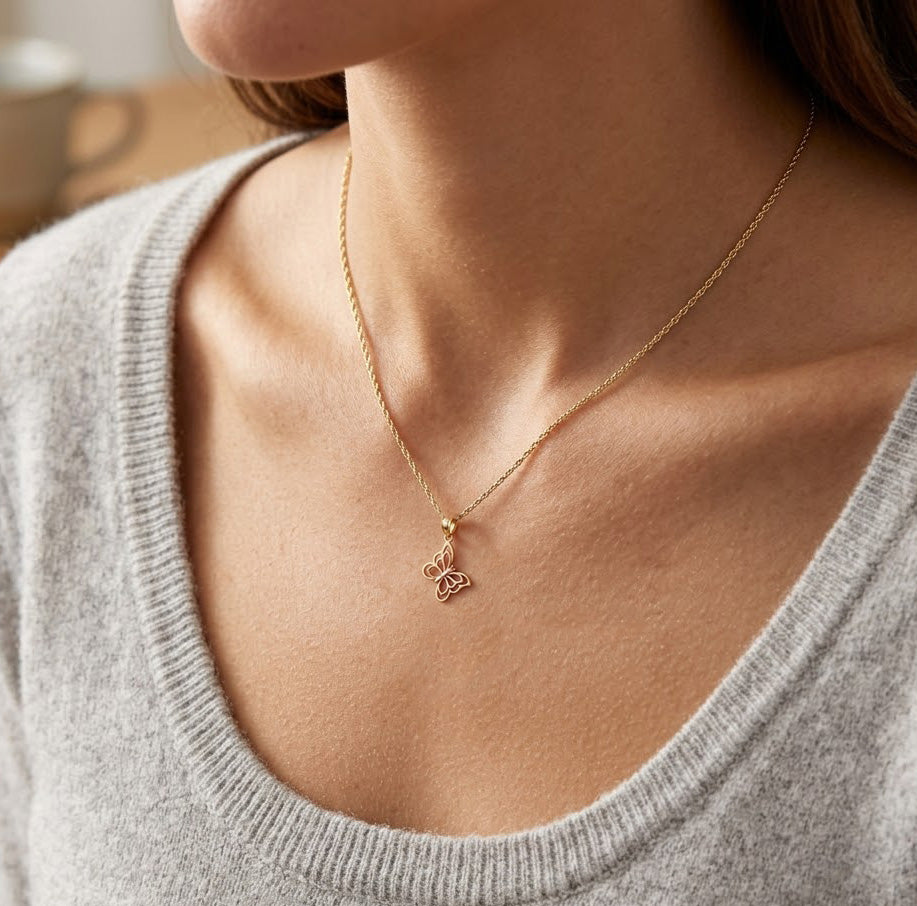 Gold necklace with a small pendant worn by a person in a gray sweater.