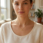 Woman wearing a gold necklace with a small dragonfly pendant necklace 