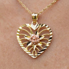 Gold heart-shaped pendant with floral design on a chain against a skin background