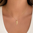 [group: large]A delicate gold chain necklace with a textured wing pendant, worn by a model in a white ribbed top.
