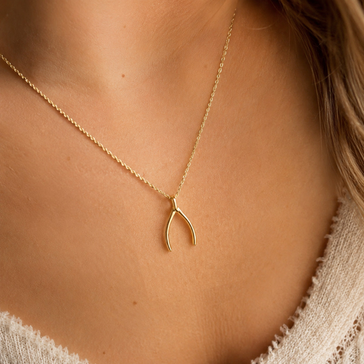 gold wishbone charm on necklace worn by female model 