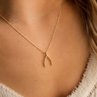 gold wishbone charm on necklace worn by female model 