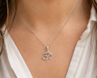 [group: silver]A sterling silver Om pendant necklace worn by a person, shown close-up against a white collared shirt.