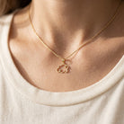 Gold necklace with a cloud pendant on a person wearing a beige top.