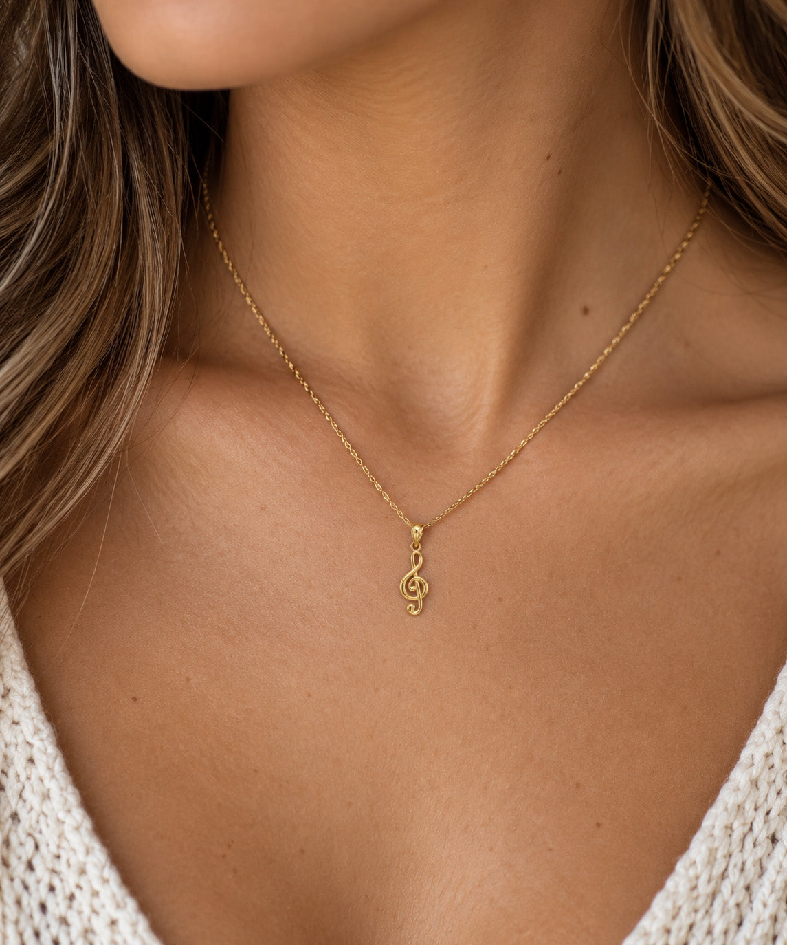close up of music note pendant worn by female model on a gold rope chain 
