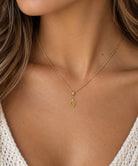 close up of music note pendant worn by female model on a gold rope chain 